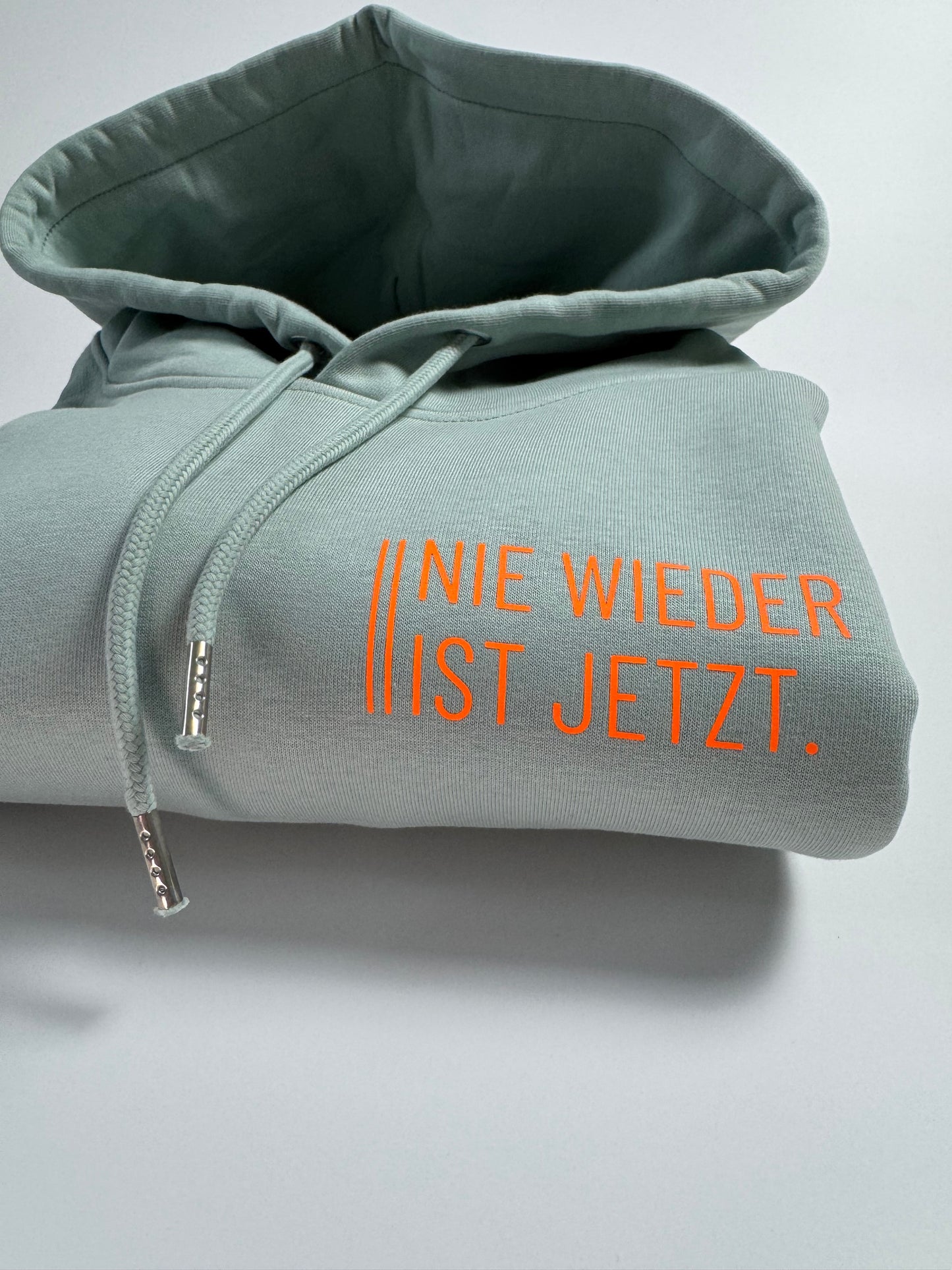 Hoodie Unisex 'Nie wieder ist jetzt.': Aloe / Neon Orange