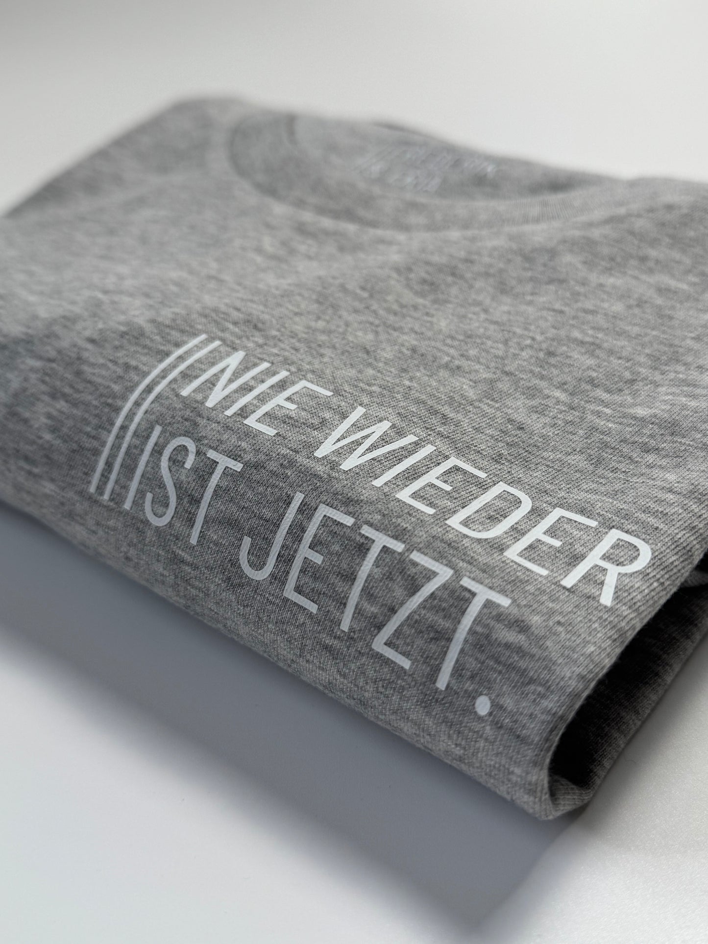T-Shirt Unisex 'Nie wieder ist jetzt.': grau / weiß